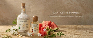 Perfume bottle with watermelon slices and flowers on a wooden surface, labeled 'Scent of the Summer'.